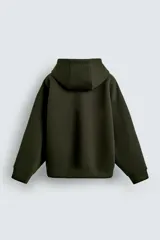 Sudadera de corte relajado confeccionada en tejido técnico con elasticidad y efecto neopreno. Presenta capucha ajustable con cordones, cierre frontal de cremallera de doble dirección, bolsillos tipo canguro y terminaciones en rib.