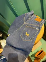 Bombacha de campo Sierra Mora confeccionada en denim de algodón, de tiro medio, con bolsillos y bordado de un caballo en el bolsillo trasero. Cuenta con pretina con botones, cierre delantero y puños ajustables con botones.