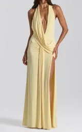 Vestido largo amarillo de diseño fluido, con escote halter pronunciado en V, drapeado en la cintura y una abertura lateral profunda en la pierna.