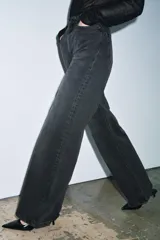 Jeans de tiro alto con corte wide leg y largo completo. Presenta diseño de cinco bolsillos, trabillas en la cintura y cierre frontal con cremallera y botón, con un acabado de efecto lavado.