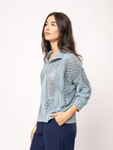 Sweater tejido de algodón color crudo, con cuello polo y escote en V. Diseño con ochos verticales en delantera, espalda y mangas, y punto abierto.