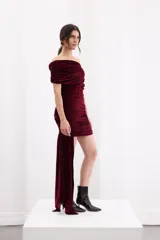 Vestido corto negro de terciopelo, con diseño asimétrico de un solo hombro, frunces en el cuerpo y un detalle lateral largo en forma de lazo.