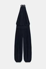Mono largo negro con cuello halter, hombros descubiertos, parte superior drapeada y piernas anchas con bajo acabado en puño elástico.