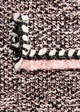Chaqueta de tweed con diseño recto y cuello redondo. Presenta cierre frontal con botones, manga larga y cuatro bolsillos de solapa en la parte delantera. Destaca por sus terminaciones deshilachadas y ribetes en contraste.