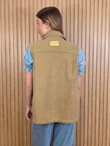 Chaleco de denim 100% algodón en color negro gastado, con cuello camisero, cierre frontal de botones metálicos y bolsillos delanteros con solapa.