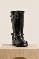 Bota de caña media de cuero color marrón oscuro, con diseño slouchy, hebillas metálicas decorativas y tachas alrededor del tobillo y en la parte superior. Cuenta con taco bajo y cuadrado.