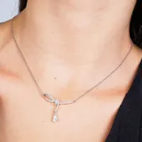 Collar plateado con dije en forma de lazo con incrustaciones de strass y dije colgante de cristal en forma de lágrima.
