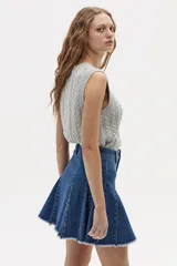 Chaleco de punto color gris melange, con cuello redondo, sisa amplia y largo a la cadera. Presenta un diseño de ochos tradicionales.