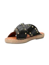 Sandalia tipo ojota con base de yute, tiras cruzadas de cuero negro con tachas doradas y hebilla metálica decorativa.