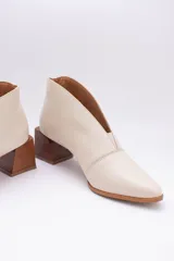 Botines de cuero color beige con diseño de tajo frontal, punta fina y taco cuadrado de madera.