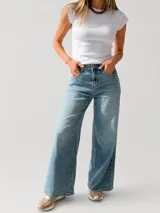 Pantalón de jean con corte wide leg y tiro medio-alto. Presenta un lavado gris azulado desgastado con acabado vintage y ruedo desflecado.