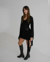 Vestido corto negro de tejido de punto con textura, escote cuadrado y mangas largas acampanadas. Presenta un diseño ajustado con detalle de lazo lateral en la cintura.