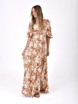 Vestido largo marrón con estampado floral blanco, escote en V cruzado y mangas cortas amplias.