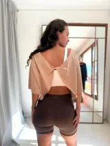 Remera corta de manga corta color celeste, con escote amplio en la espalda que se anuda en la parte inferior, dejando ver un top deportivo amarillo con tiras cruzadas.