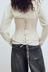 Top estilo corset de escote corazón y hombros descubiertos, con varillas interiores para estructura. Presenta cierre frontal con ganchos metálicos y ajuste posterior mediante cordones cruzados.