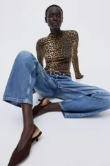 Top de punto con cuello alto y manga larga, con diseño de estampado de leopardo y terminaciones con remate sobrehilado en puños y bajo.