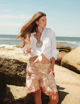 Shorts de brocato con estampado floral en tonos rosados y beige, con terminación de flecos en el ruedo.