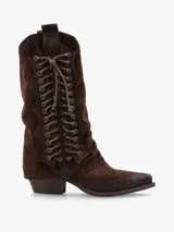 Bota de caña media de gamuza color marrón oscuro, con punta cuadrada y taco bajo. Presenta un sistema de cordones frontal con ojales metálicos que recorre gran parte de la caña, y un diseño con costuras en zigzag en los paneles laterales.