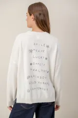 Sweater de punto color gris con bordado en color verde neón en el pecho con la frase 'GOOD KARMA'. Presenta cuello redondo, mangas largas y un diseño con tajos laterales en el ruedo.