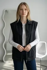 Maxi chaleco de jean color negro con cierre frontal, cuello camisero y diseño sin mangas.