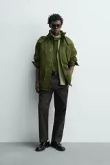 Parka técnica color verde militar de corte relaxed fit con cuello subido y capucha desmontable. Cuenta con bolsillos con solapa en el pecho y en la cadera, cintura ajustable con cordón y cierre frontal de cremallera oculta por solapa con botones a presión. Incluye un chaleco interior desmontable acolchado.