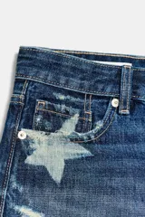 Shorts de denim de tiro medio en color azul, con diseño de estrellas deslavadas, roturas y terminaciones deshilachadas. Cuenta con trabillas, cinco bolsillos y cierre frontal con cremallera y botón metálico.