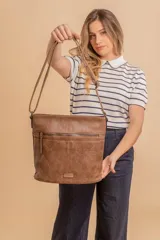 Bandolera de tamaño mediano confeccionada en símil cuero color marrón, con correa larga regulable, cierre principal y bolsillo frontal con cierre.