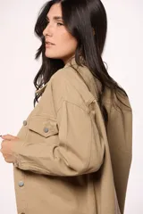 Sobrecamisa de jean color marrón, con cierre frontal de botones metálicos, bolsillos frontales con solapa y ruedo deshilachado.