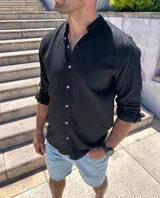 Camisa negra de lino con cuello mao y manga larga con puños abotonados. Cierre frontal con botones a tono.