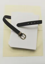 Cinturón negro de cuero con hebilla metálica dorada de diseño clásico y formato redondeado.