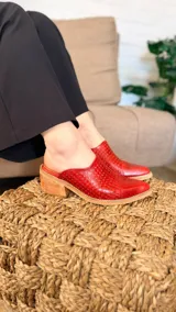 Zuecos de cuero color rojo, con diseño perforado en el empeine, puntera lisa redondeada, talón descubierto y taco ancho de madera.