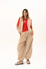 Pantalon tipo babucha de color beige, con silueta relajada y acabado suave tipo piel de durazno. Presenta cintura regulable con cordón y elástico en los tobillos que genera una forma abuchonada.