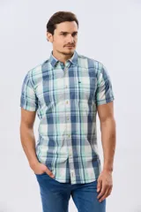 Camisa de manga corta con estampado de cuadros en tonos celestes, azules, blancos y verdes, con cierre frontal de botones y bolsillo ojal en el pecho.