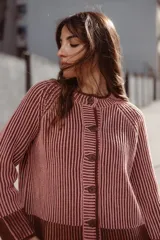 Saco de punto vanizado, tejido en dos colores con efecto bicolor a rayas verticales, cuello redondo, manga larga y cierre frontal con botones negros.