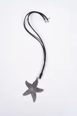 Collar con dije de estrella de mar texturizado en tono plateado envejecido, suspendido de un cordón negro de múltiples hilos con cierre ajustable.