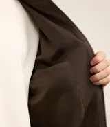 Campera bomber color beige, con cuello alto, cierre frontal con cremallera, bolsillos laterales y puños y cintura elastizados.