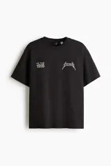 Remera negra de corte holgado con hombros caídos y cuello redondo. Presenta un estampado frontal pequeño con el logo de Metallica y la inscripción 'U.S. Tour 1985'.