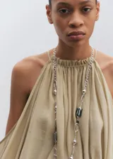 Blusa corta de tejido mezcla, color verde, con diseño de hombros descubiertos, mangas largas abullonadas, cuello redondo fruncido con lazo en la espalda y espalda abierta.