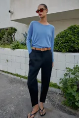 Pantalón tobillero azul marino de tiro medio, con pinzas delanteras, bolsillos frontales, falsos bolsillos con solapa en la espalda y cierre frontal con cremallera, botón y gancho. Incluye cinturón de cuero sintético tostado con hebilla metálica dorada.