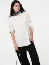 Camisa color crema de fit básico, confeccionada en 55% lino y 45% viscosa. Cuenta con abotonadura central delantera y mangas 3/4 con botón.