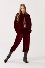 Pantalón de terciopelo color borgoña, de tiro alto, con cintura elástica en la espalda, cierre frontal, bolsillos laterales y piernas anchas.