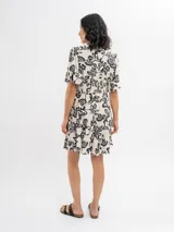 Vestido corto de viscosa en color beige con estampado floral en negro, escote en V con botones frontales, mangas cortas y falda amplia con volados en capas.