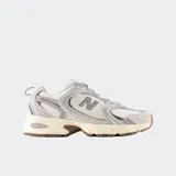 Championes New Balance modelo 530, con diseño retro inspirado en el running. Presentan una parte superior de malla transpirable con superposiciones de cuero sintético en tonos gris claro y blanco, entresuela con tecnología ABZORB para mayor amortiguación y suela de goma en color marrón.