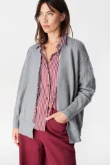 Saco abierto de punto gris con textura geométrica en relieve, mangas largas con puños acanalados y corte holgado.