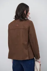 Blazer de gamuza color marrón, con solapas clásicas, cierre frontal de tres botones y bolsillos laterales con solapa.