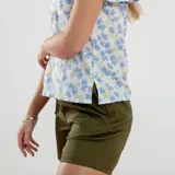 Blusa blanca con estampado de flores azules y verdes, cuello redondo con abertura en forma de gota y mangas cortas amplias.