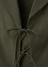 Camisa sin mangas de lino y algodón color verde militar, con cuello solapa y cierre frontal con múltiples lazos.
