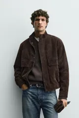 Cazadora regular fit de cuero con acabado serraje en color marrón, cuello subido, bolsillos de plastrón con solapa en la cadera y cierre frontal de cremallera oculta por solapa con botones a presión.