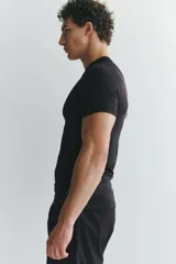 Remera deportiva de compresión color negro, con cuello redondo, mangas raglán cortas y costuras planas antifricción.