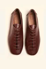 Zapatos chatos de cuero color bordó, con cordones finos y punta cuadrada.